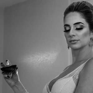 A sophisticated woman applying perfume, captured in a refined black and white image.